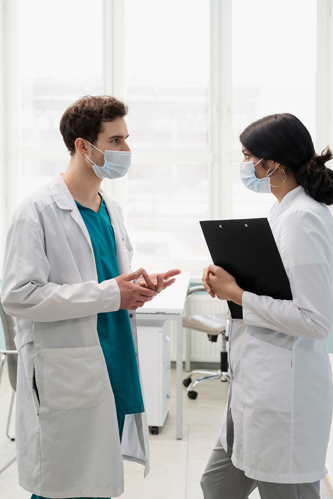 Two doctors having a discussion in a bright hospital corridor.